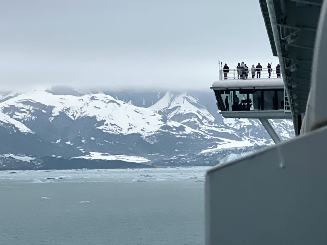 Vue d'une chaîne de montagnes enneigées de l'Alaska avec des touristes regardant le paysage depuis une zone de surveillance.