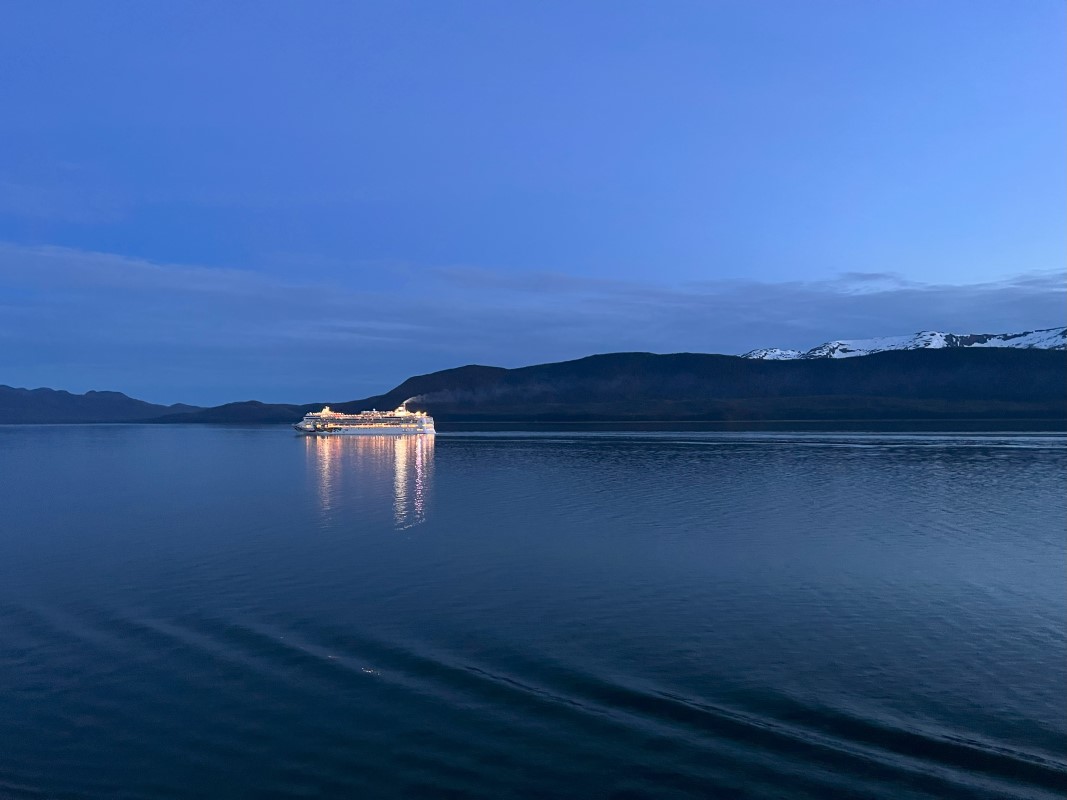 Une photo prise au crépuscule avec un bateau de croisière isolé illuminant les eaux océaniques.